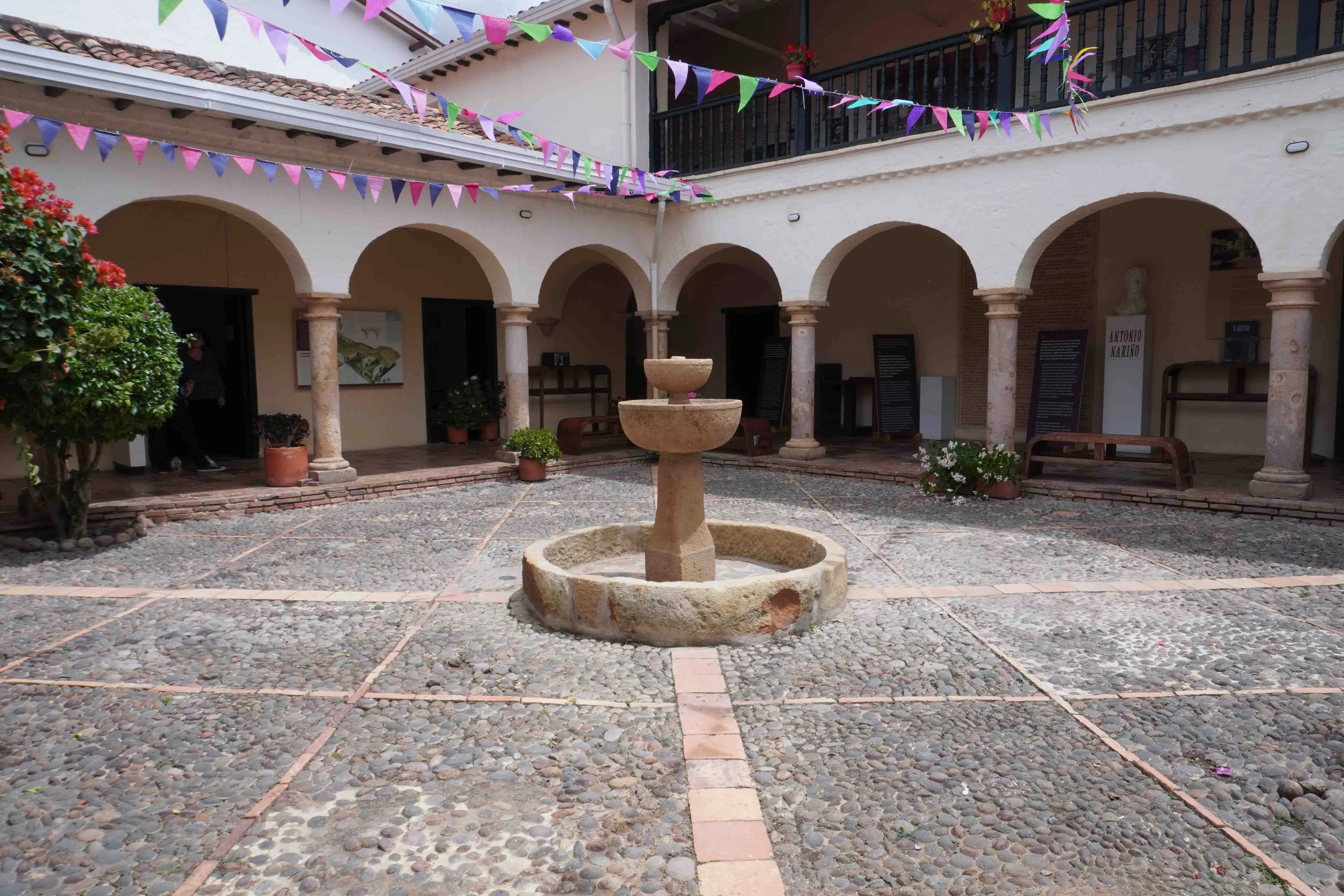 Patio central de la Casa Museo Antonio Nariño: la fuente de piedra sobre el empedrado y la arcada de columnas alrededor