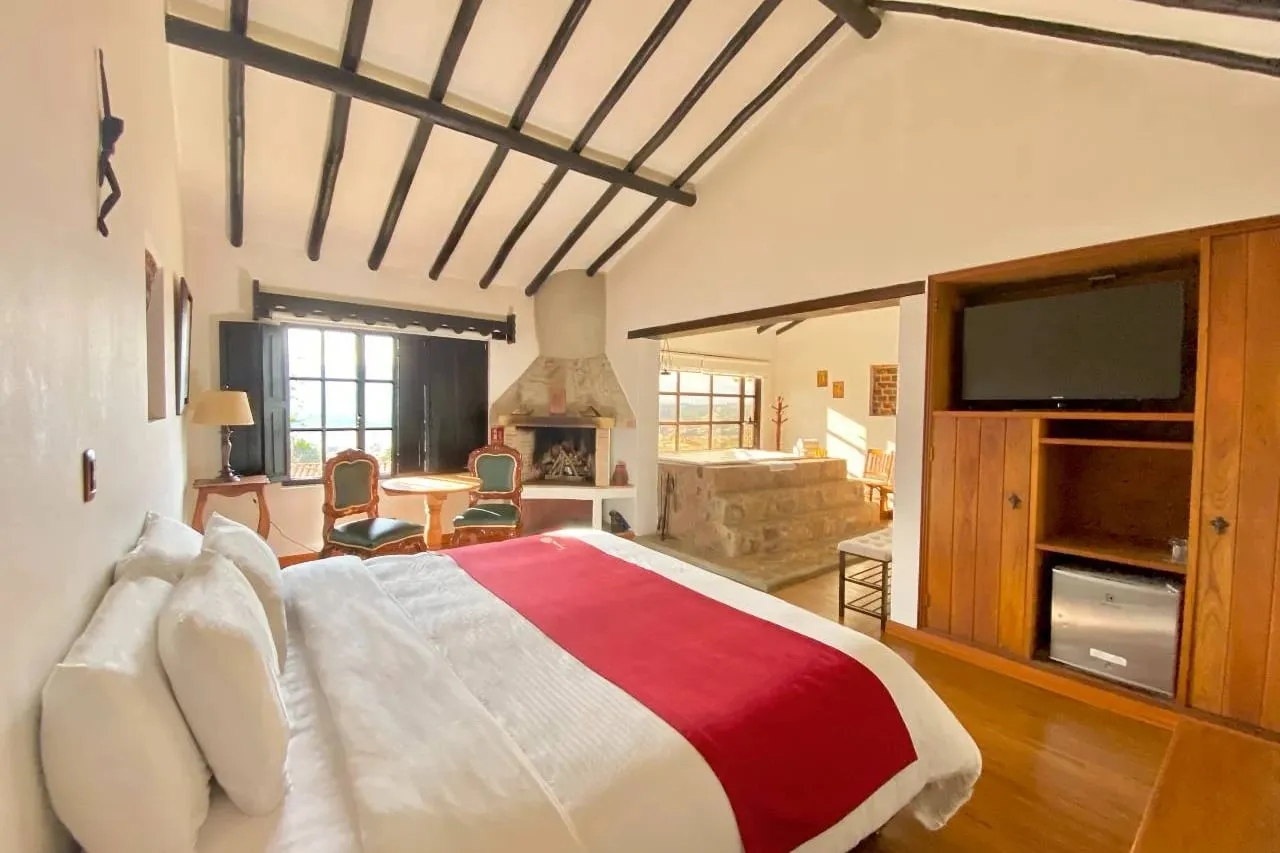 Suite de la Hospedería Duruelo con techo de vigas de madera, chimenea de piedra y cama doble