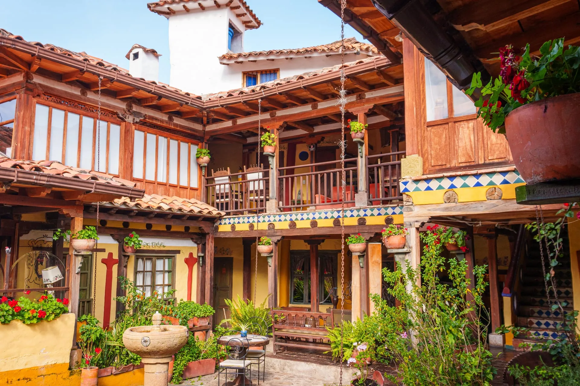 Patio colonial de La Posada de San Antonio, con balcones de madera, flores y una fuente de piedra